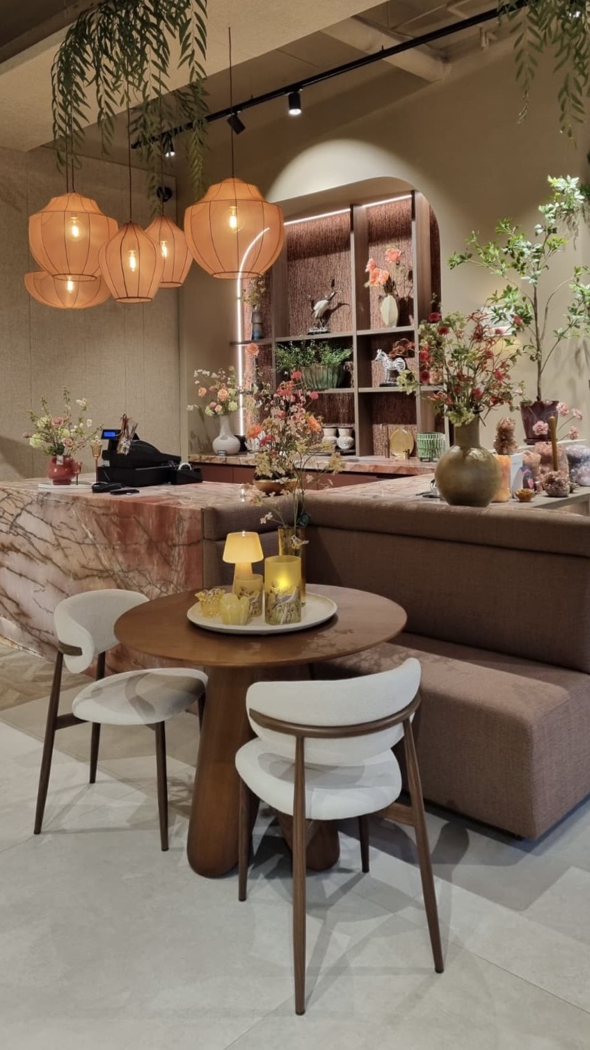 Uitzicht op de ruime, moderne bedrijfskantine van de Van der Werff Groep, met op de voorgrond een eettafel op een bakstenen vloer en daarachter een tafeltennistafel en een opvallende groene moswand. Achterin is een afgesloten vergaderruimte of werkplek zichtbaar. Diverse hanglampen hangen aan een plafond met houten balken. Aan de rechterkant bevindt zich een bakstenen muur.