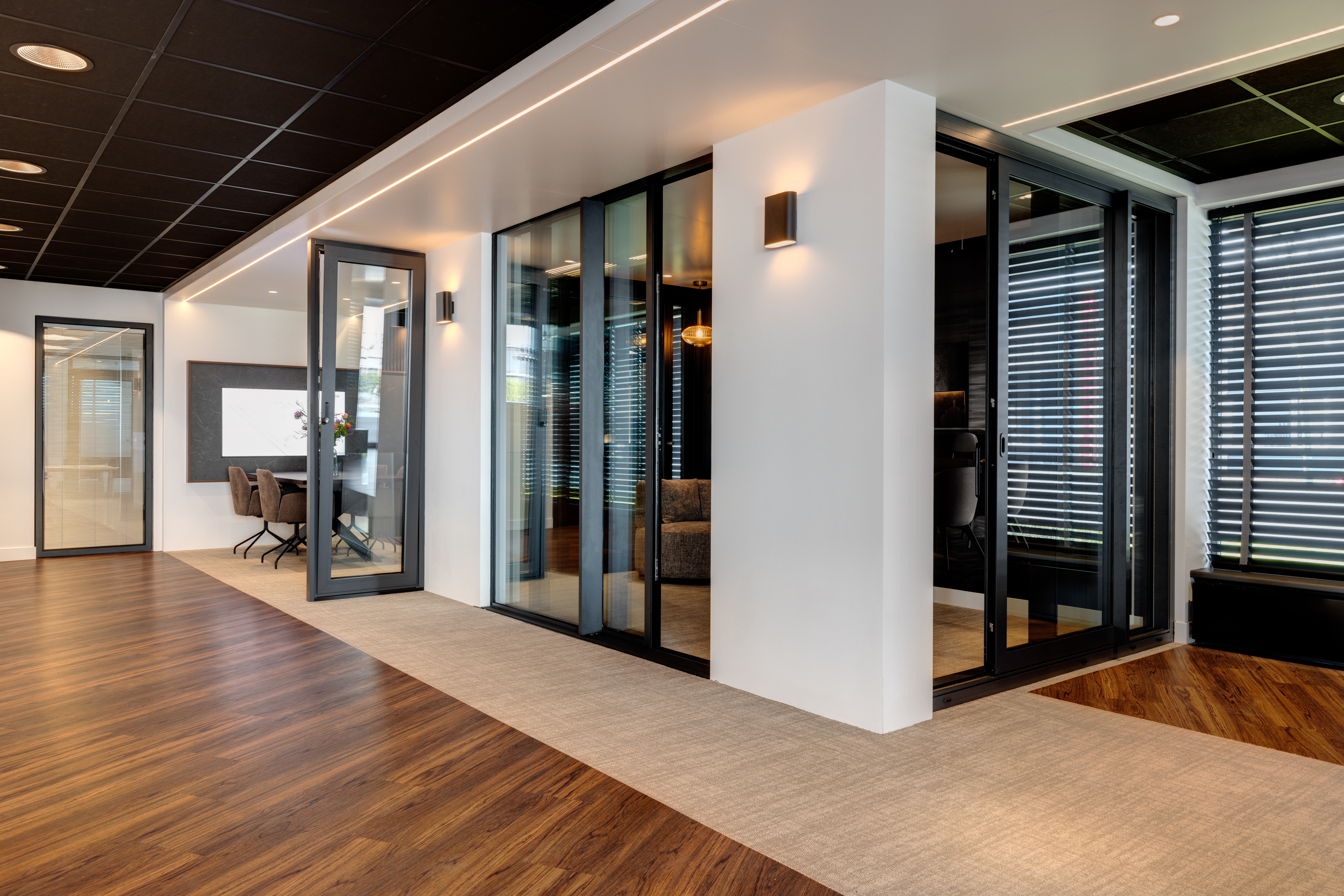 Innovatieve productpresentatie in de Lieftink Showroom waarbij diverse zwart metalen kozijnen en deuren van Lieftink naadloos zijn ingebouwd in witte tussenmuren voor een realistische beleving.