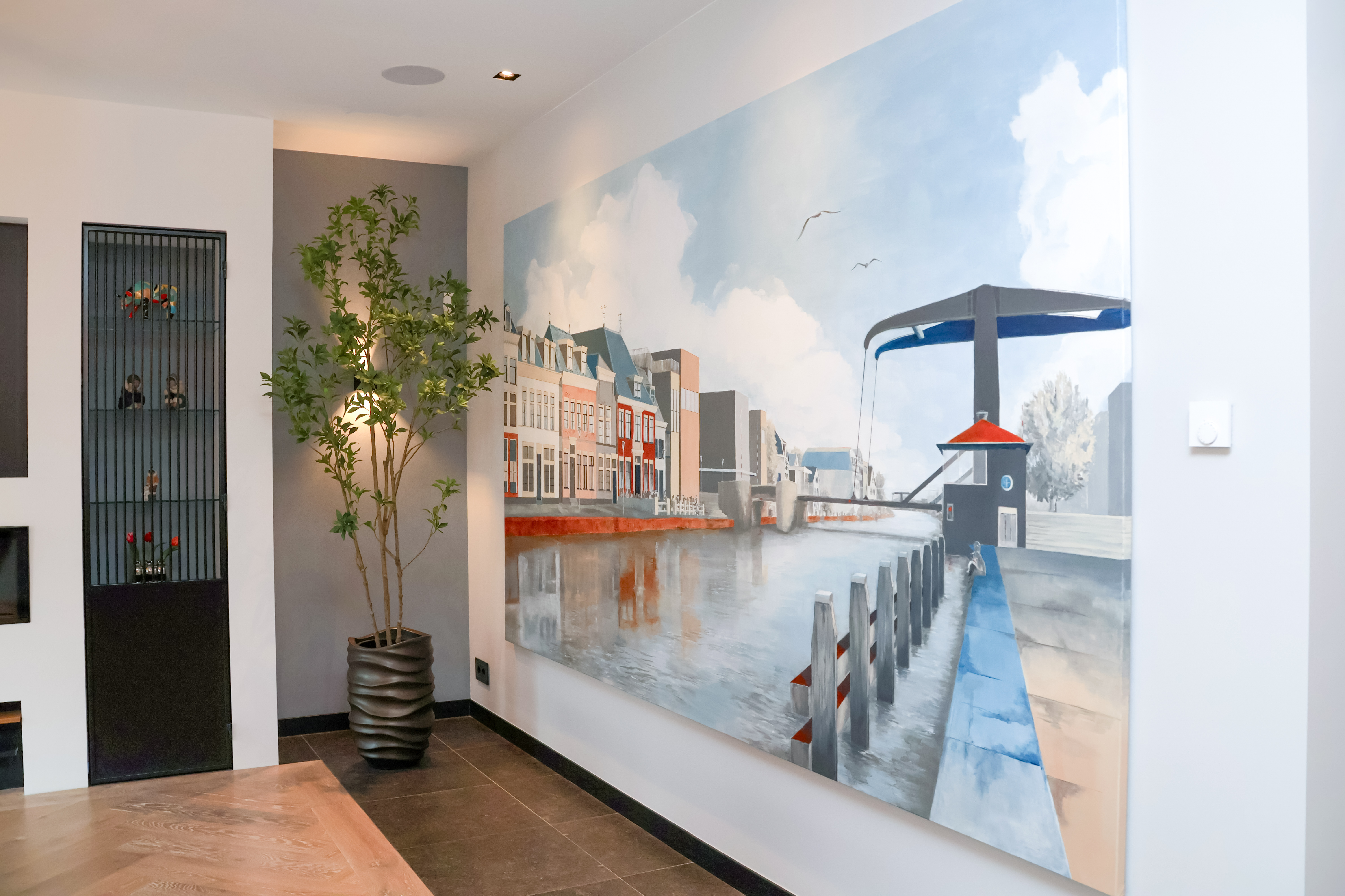 De entree van het kantoor van de Van der Werff Groep, met een stoere zwarte spiltrap op een bakstenen vloer en opvallende, verlichte verticale plantenwanden voor een frisse en warme uitstraling.