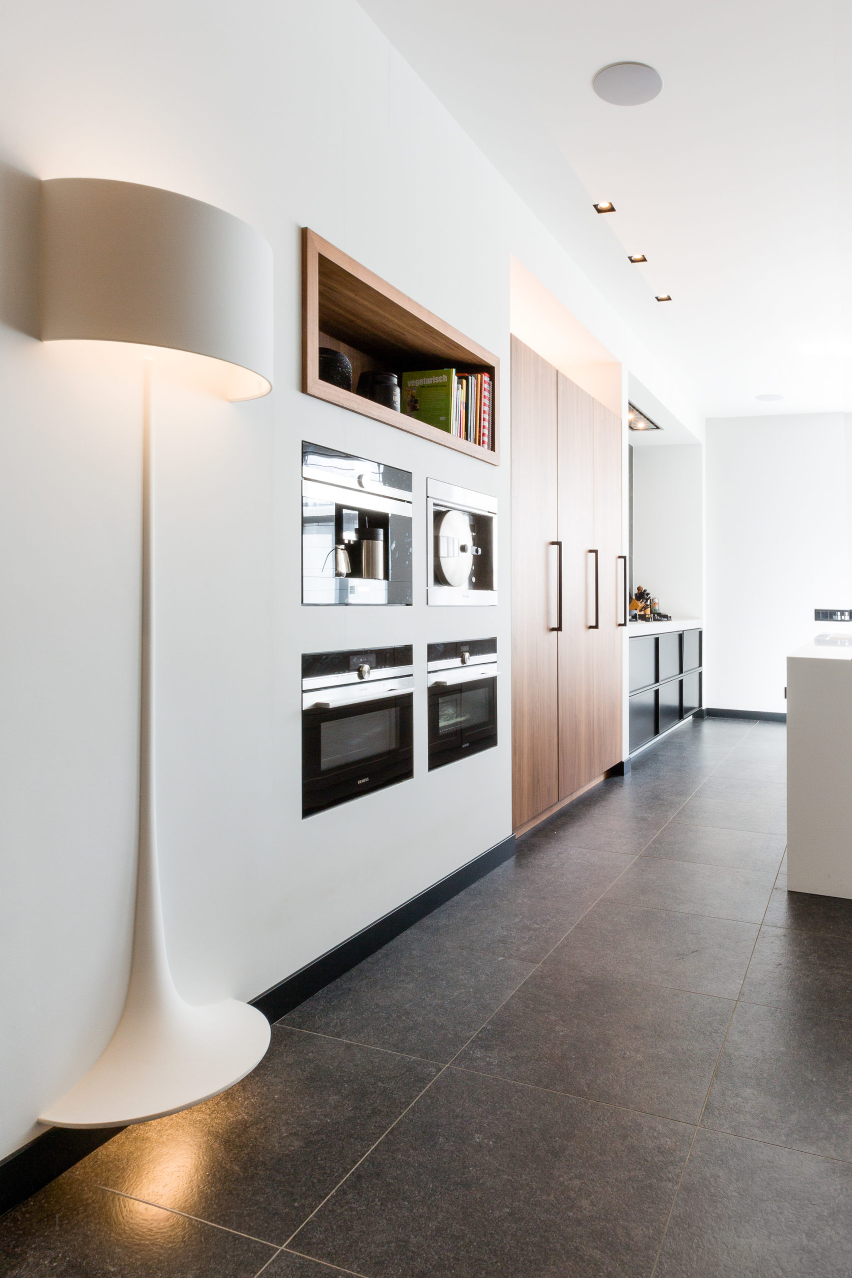 Kijkje in een moderne vergaderruimte van de Lieftink Showroom door een geopende zwarte vouwpui, compleet met een lange houten tafel, designstoelen en een strak lichtplan.