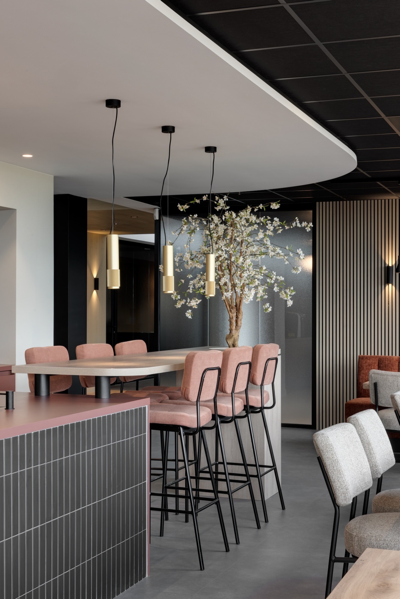 Kijkje in een moderne vergaderruimte van de Lieftink Showroom door een geopende zwarte vouwpui, compleet met een lange houten tafel, designstoelen en een strak lichtplan.